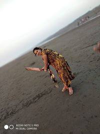 Full length of person on sand at beach against sky