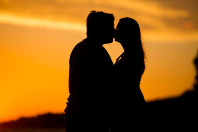 Silhouette couple against orange sky during sunset