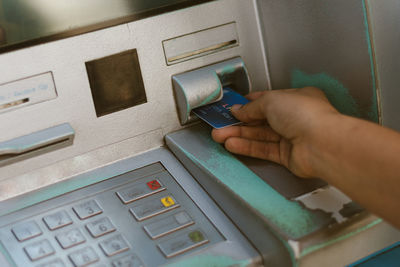 Cropped hand inserting credit card in atm machine