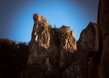 Low angle view of rock formation against clear blue sky