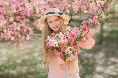 Portrait of woman standing by pink flowering plant