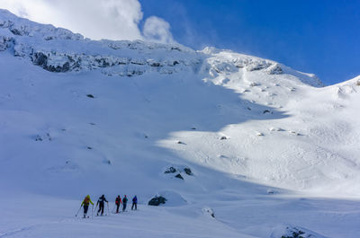 People skiing on snowcapped mountain against sky