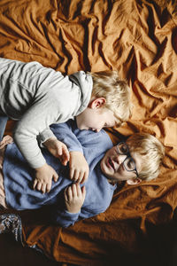 Happy siblings playing and lying on bed at home