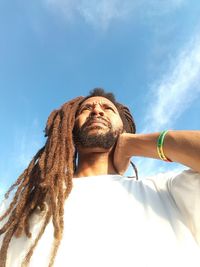 Low angle view of man with dreadlocks against sky