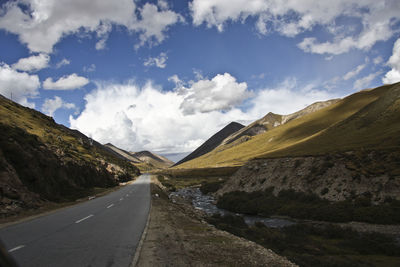 Road leading towards mountains against sky