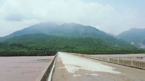 Road leading towards mountains against sky