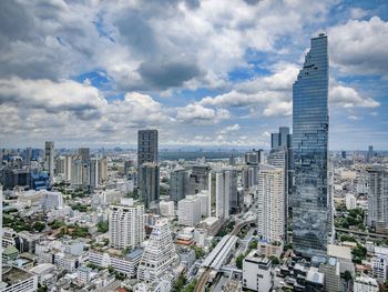 Aerial view of buildings in city against cloudy sky