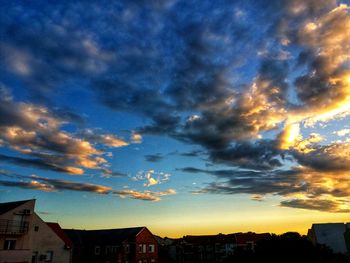 Houses in city against sky at sunset