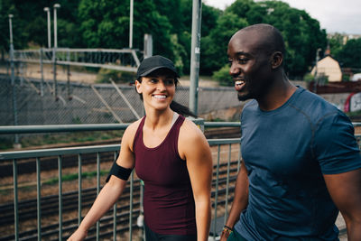 Smiling male and female athlete walking on footbridge in city