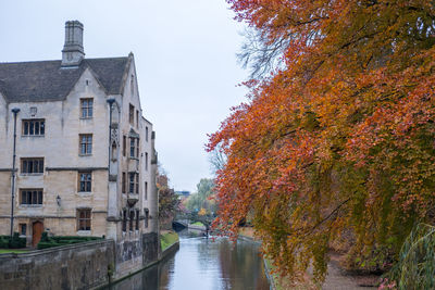 River amidst buildings against sky during autumn