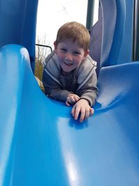 Portrait of boy enjoying on blue slide