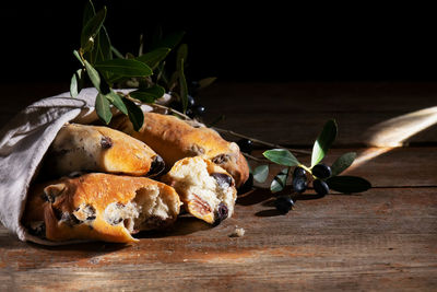 Traditional italian puccia bread with black olives in a cotton bag on a wooden background