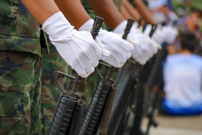 Cropped image of army soldiers holding riffles while standing outdoors