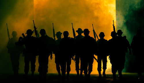Silhouette soldiers standing by smoke at night