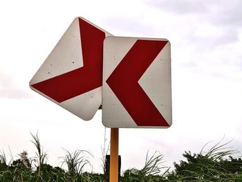 Close-up of road sign against sky