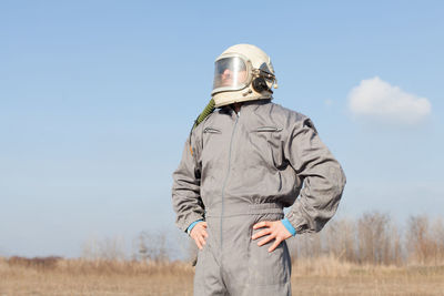 Mid adult man wearing protective workwear standing on field against sky