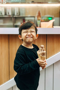 A boy is holding an ice cream with a happy smile