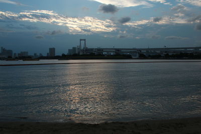 Sea by city against sky during sunset