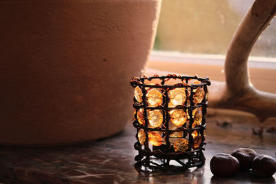 Close-up of illuminated candles on table against wall