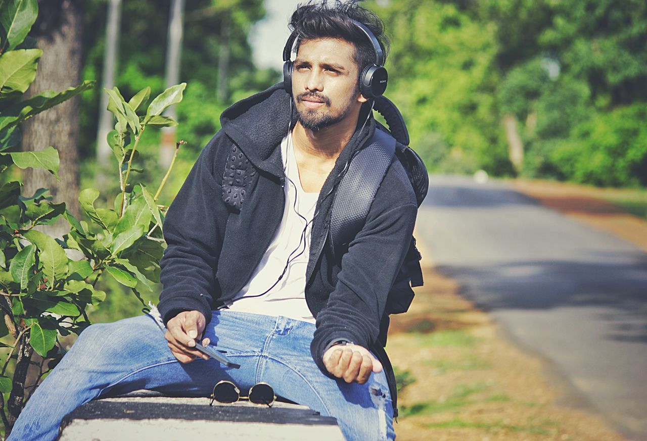 lifestyles, casual clothing, young adult, leisure activity, person, young men, looking at camera, portrait, standing, front view, focus on foreground, three quarter length, tree, smiling, jacket, sitting, outdoors, day