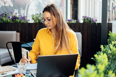 Time management for freelancers. woman freelancer writes in a notebook and working with laptop