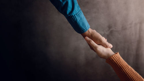 Close-up of person holding hands against wall