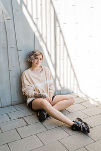 Portrait of woman sitting by wall outdoors