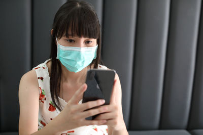 Woman wearing mask using mobile phone