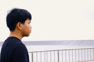 Side view of young man looking away against wall