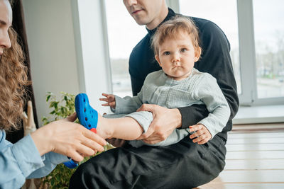 Mom and dad put shoes on the baby. high quality photo