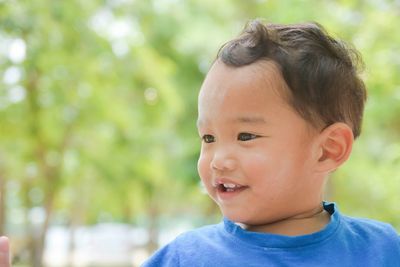 Close-up of smiling baby boy looking away at public park