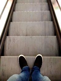 Low section of man standing on escalator