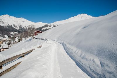 Scenic view of snow covered mountains against blue sky