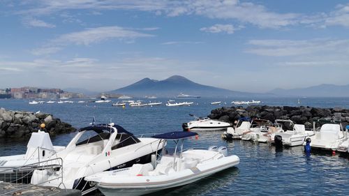 Boats moored in sea by city against sky