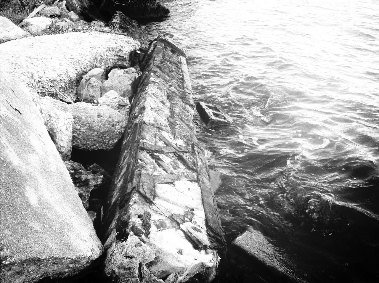 water, high angle view, rock - object, rippled, sea, nature, river, tranquility, day, outdoors, beauty in nature, rock, lake, no people, tranquil scene, sunlight, wood - material, stone - object, scenics, textured