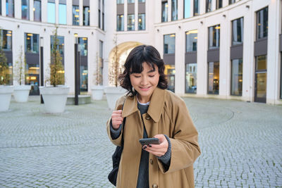 Young woman using mobile phone in city