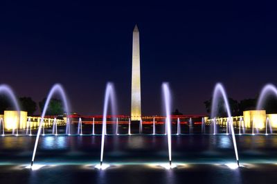 Blurred motion of illuminated fountain against monument at night