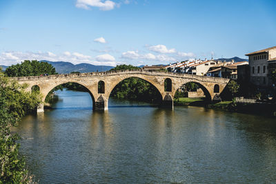 Arch bridge over river against sky in city