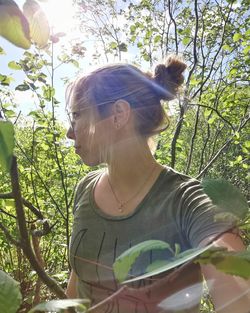 Woman standing by tree against plants