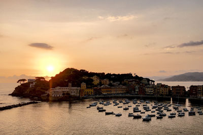 Scenic view of river by city against sky during sunset