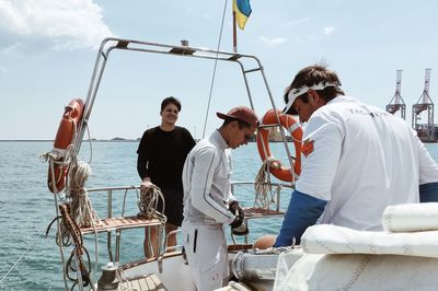 People on boat in sea against sky