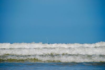 Waves in sea against clear blue sky