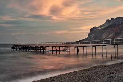 Pier over sea against sky during sunset