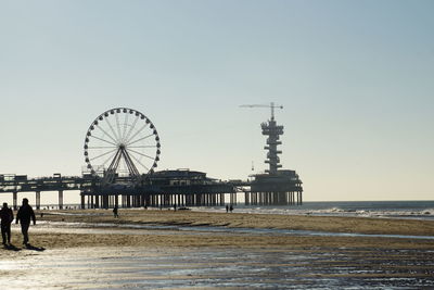 Ferris wheel on beach against clear sky