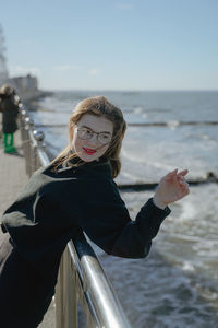 Portrait of young woman standing against sea
