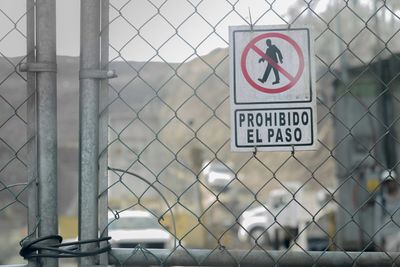 Close-up of information sign on chainlink fence