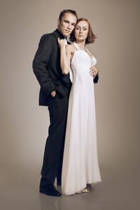 Full length portrait of couple standing against gray background