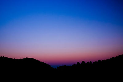 Scenic view of silhouette trees against clear sky at sunset