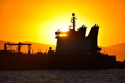 Silhouette ship on sea against sky during sunset