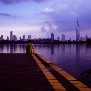 Rear view of man looking at cityscape against sky